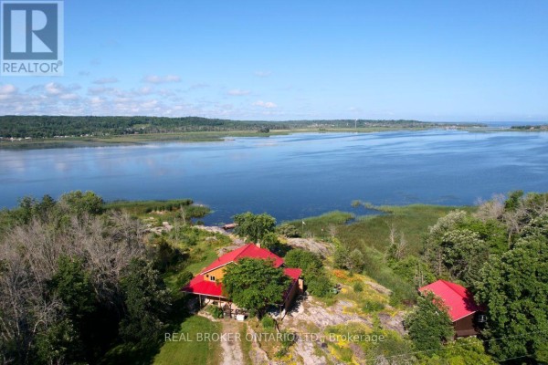 Aerial view of property with red-roofed house, frozen lake, and snow-covered landscape. - 1866 Tay Bay Road, Severn