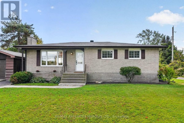 View of the front entrance of a brick bungalow with a concrete walkway and steps. - 18696 County Road 2 Road, South Glengarry