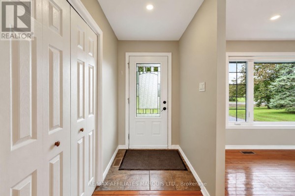 Interior hallway with a white door, tiled floor, and large closet doors leading to a living area. - 18696 County Road 2 Road, South Glengarry