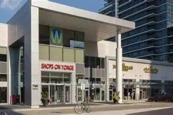 Street-level view of the "Shops On Yonge" entrance with glass doors, modern architecture, and a bicycle parked outside. - 187 - 7181 Yonge Street E, Markham