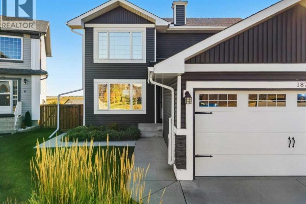 Close-up front view of a dark grey house with a white garage door and stone accents. - 187 Covington Close Ne, Calgary