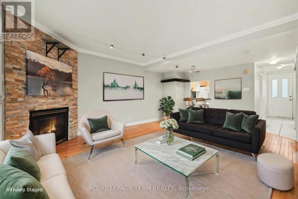 Virtually staged living room with a fireplace, sofa, chairs, coffee table, and dining area. - 187 Monterey Drive, Ottawa