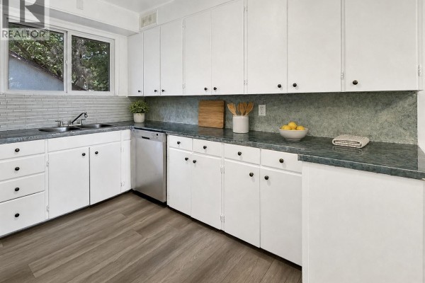 Kitchen with white cabinets, stainless steel dishwasher, and a double sink. - 1872 101st Street, North Battleford