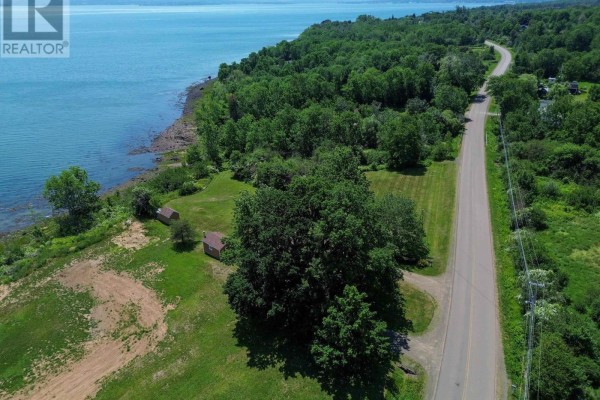 Aerial view of the property featuring the bungalow, outbuildings, and the road leading past the lot. - 1878 Granville Road, Port Wade