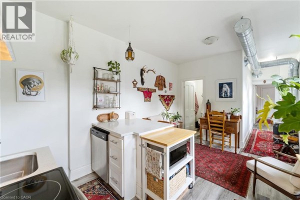 Kitchen with stainless steel appliances, a breakfast bar with stools, and white cabinetry. - 188-190 Caroline Street S, Hamilton