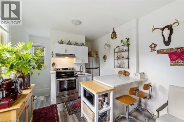Living room with a sofa, coffee table, fireplace, and a window view. - 188-190 Caroline Street S, Hamilton