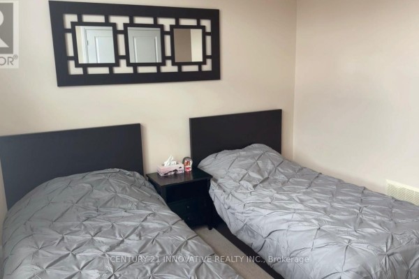 A bedroom with two twin beds with grey comforters and black headboards. - 188 Barkley Crescent, Oshawa