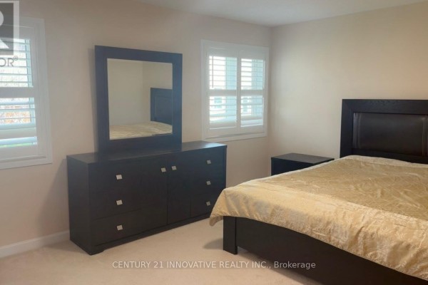 A bedroom with a dresser, bed, and two windows with white shutters. - 188 Barkley Crescent, Oshawa