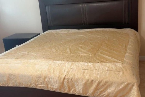 A queen-size bed with a brown leather headboard and a gold comforter. - 188 Barkley Crescent, Oshawa