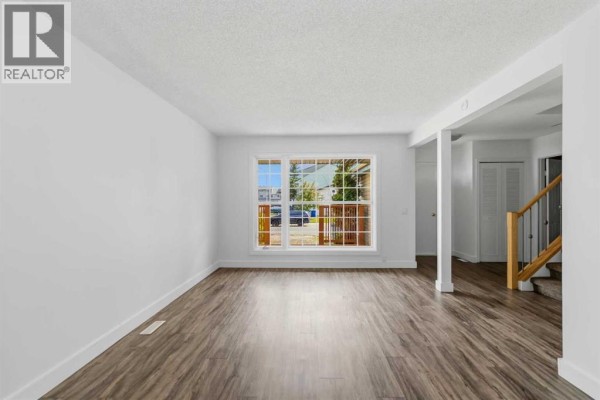 Living room with white walls, dark wood laminate flooring, and a large window. - 188 Windsor Drive, Fort Mcmurray