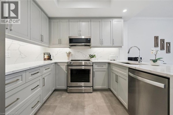 U-shaped kitchen with light gray cabinetry, stainless steel appliances, and a breakfast bar. - 1880 Gordon Street Unit# 707, Guelph