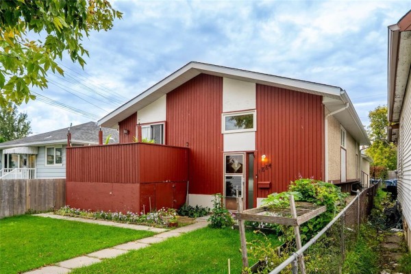 View of the side and front of a red and white split-level house with garden elements. - 1884 Ross Avenue W, Winnipeg