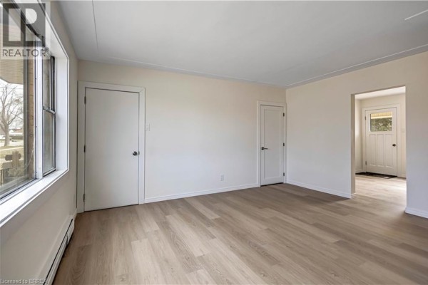 Empty room featuring light wood laminate flooring and two white doors, one single and one double. - 1887-1889 Wavell Street, London