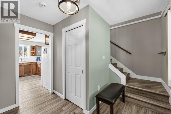 Interior entryway with light grey walls, a sage green accent wall, a staircase, and a closed white door. - 1888 Nicolls Road, Merritt