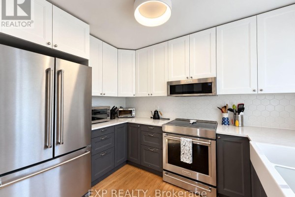 Modern kitchen with stainless steel appliances, white and dark grey cabinetry, and a tile backsplash. - 189 Dunbarton Court, Ottawa