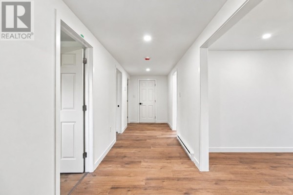 Interior hallway with white walls, recessed lighting, and wood-look laminate flooring. - 189 Quigleys Line, Bell Island