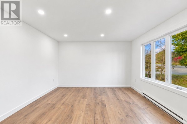 Empty room with white walls, recessed lighting, and a large window with a view of trees. - 189 Quigleys Line, Bell Island