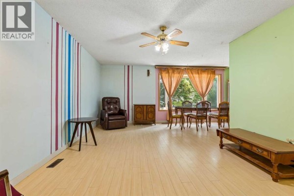 Living and dining room with light wood floors, colorful walls, and curtains. - 189 Whitaker Close Ne, Calgary