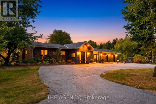 Front exterior of a brick house with a paved driveway at dusk. - 1890 Concession 7 Road, Adjala Tosorontio