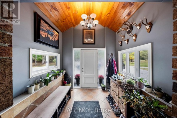 Interior entryway with a white door, wood ceiling, and mounted deer heads. - 1890 Concession 7 Road, Adjala Tosorontio