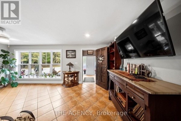 Living room with large windows, tile floor, and a mounted television. - 1890 Concession 7 Road, Adjala Tosorontio