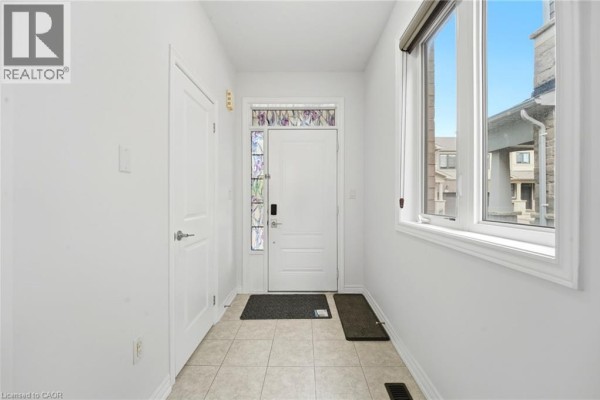 Interior view of the townhouse entryway with white walls, tiled floor, and decorative glass door. - 1890 Rymal Road Unit# 49, Hamilton