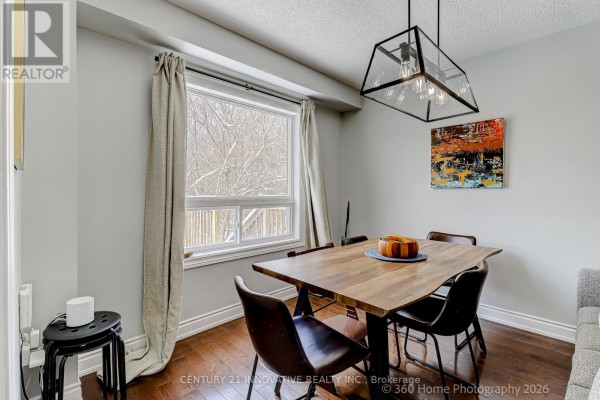 Dining area with wooden table, dark chairs, and window view of snow. - 1896 Woodgate Court, Oshawa