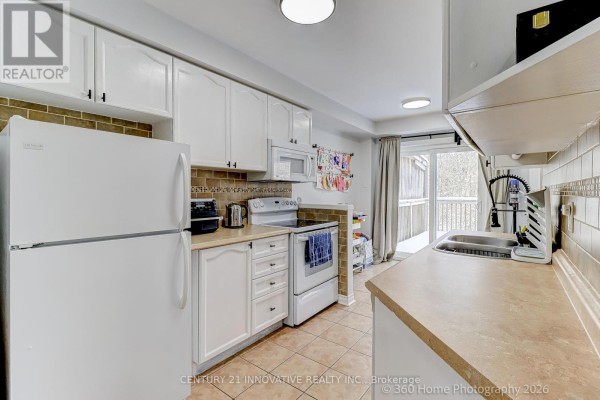 White kitchen with beige tiled backsplash and stainless steel appliances. - 1896 Woodgate Court, Oshawa