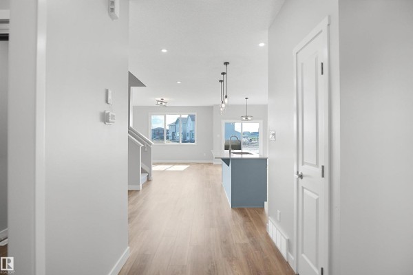 Open living area with kitchen island, pendant lights, and large windows - 18963 28 Av Nw, Edmonton