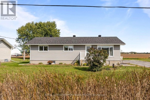Side view of a grey bungalow at 1897 Champlain Road with a grassy lawn. - 1897 Champlain Road, Clarence Rockland