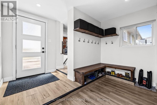 Mudroom entrance with wood bench, shoe storage, coat hooks, and light wood laminate flooring. - 1897 Champlain Road, Clarence Rockland