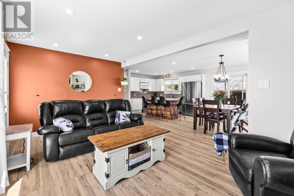 Living room with black leather sofa, accent wall, and open concept kitchen and dining area. - 1897 Champlain Road, Clarence Rockland