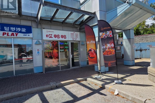 Storefront entrance with Asian signage, flag banners, and glass doors. - 19 - 4400 Sheppard Avenue E, Toronto