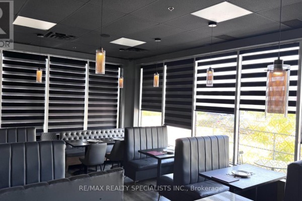 Restaurant seating area with dark gray booths, tables, and large windows with striped blinds. - 19 - 4585 Highway 7 Road W, Vaughan