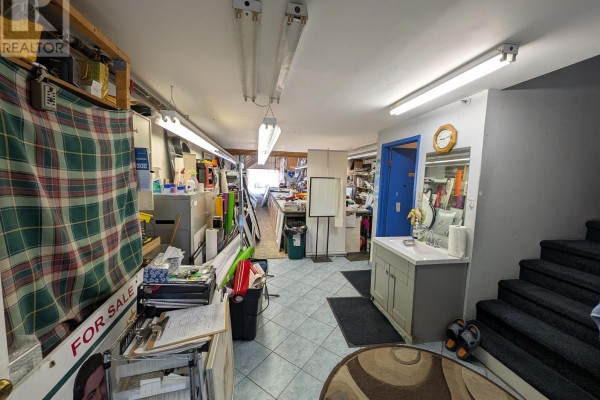 Storage area with cluttered workspaces, shelves, and stairs leading to another level - 19 - 50 Weybright Court, Toronto
