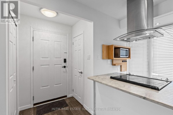 Interior view of front entryway with white doors and a granite-topped kitchen island. - 19 - 55 Arbour Glen Crescent, London East
