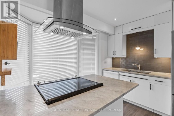 Modern kitchen with white cabinetry, stainless steel hood fan, and induction cooktop on island. - 19 - 55 Arbour Glen Crescent, London East