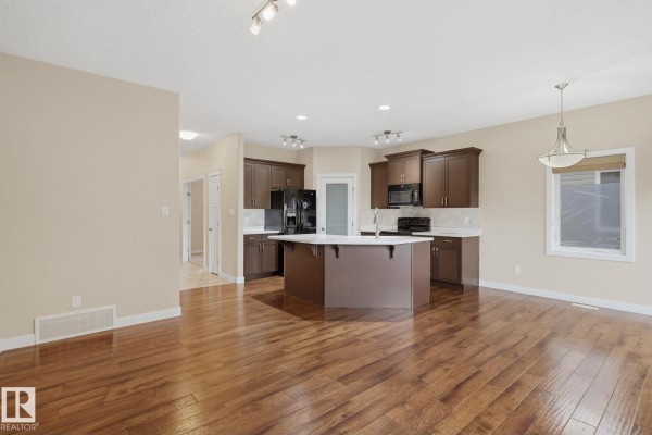 Open concept living and kitchen area with dark wood cabinets, white countertops, and hardwood floors. - #19 340 Spruce Ridge Rd, Spruce Grove