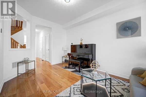 Living room with hardwood floors, a black grand piano, and a geometric rug on the floor. - 19 Begonia Street, Markham