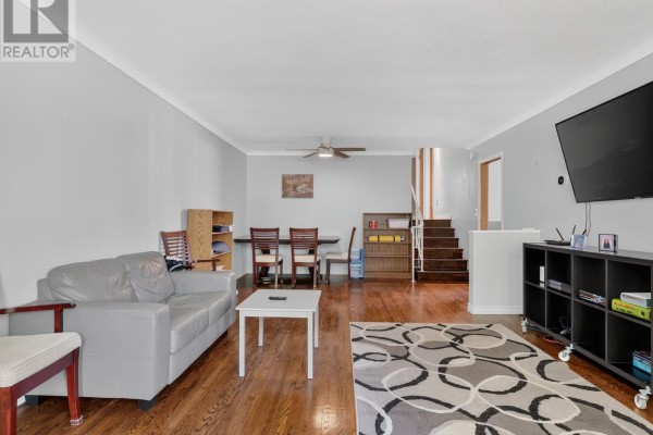 Living and dining area with hardwood floors, grey sofa, dining table, and stairs to upper level. - 19 Black Knight Road, St  Catharines