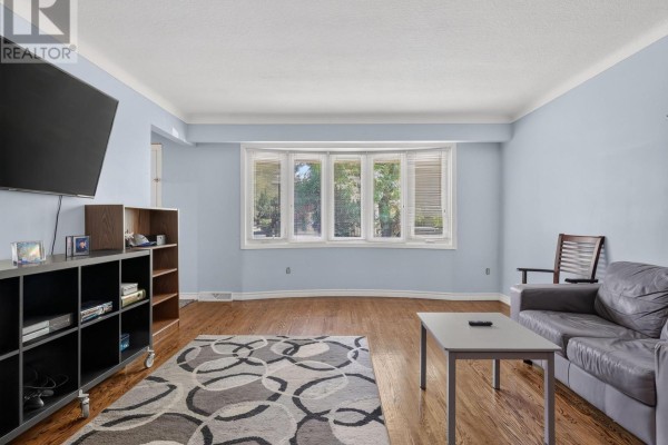 Living room with light blue walls, hardwood floors, bay window, and grey sofa. - 19 Black Knight Road, St  Catharines