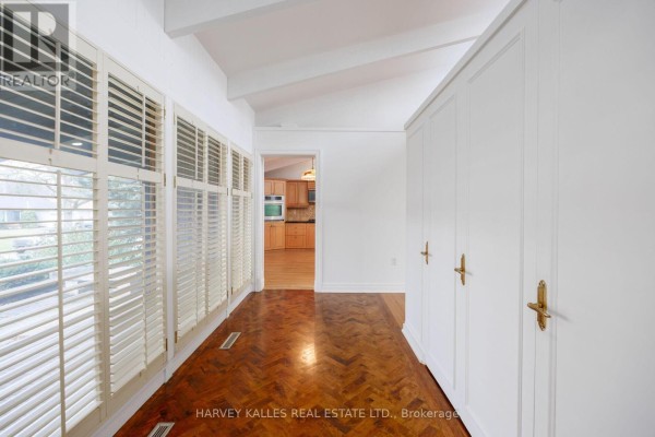 Interior hallway with white paneled walls, large louvered windows, and herringbone wood flooring. - 19 Blair Athol Crescent, Toronto