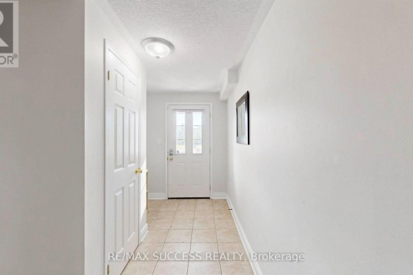 Hallway with light gray walls and beige tiled floor leading to a glass door. - 19 Boot Terrace, Toronto