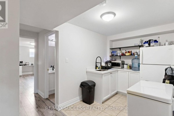 Basement kitchenette with white cabinets, a black trash can, and a white refrigerator. - 19 Boot Terrace, Toronto