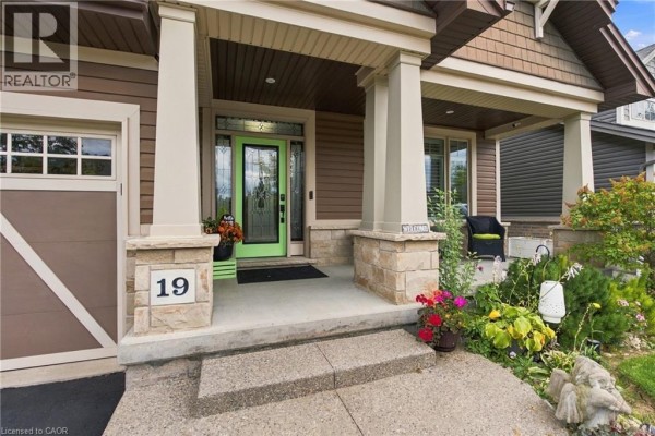Close-up of the front porch with stone pillars, a green front door, and decorative planters. - 19 Brookside Terrace, Smithville
