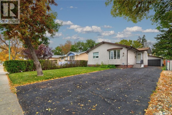 Exterior view of a bungalow with a front asphalt driveway and mature trees. - 19 Cavendish Street, Regina