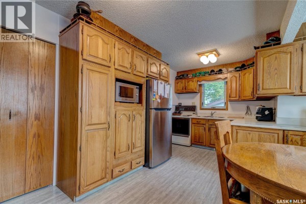 Kitchen with light wood cabinets, stainless steel refrigerator, and a view of the dining area. - 19 Cavendish Street, Regina