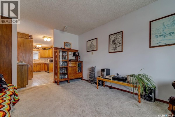 Living room with carpet, a hutch, and an open view into the kitchen. - 19 Cavendish Street, Regina