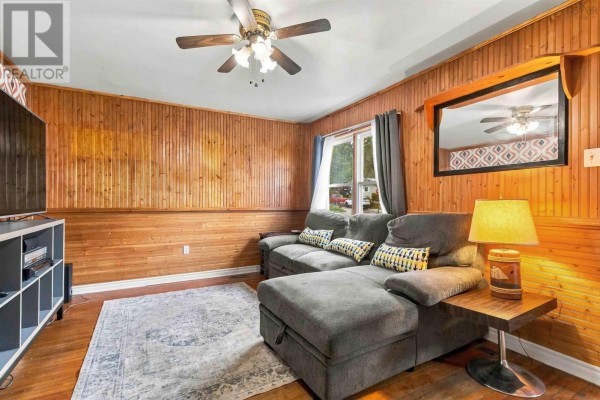 Living room with wood paneled walls, a grey sectional sofa, and a patterned accent wall. - 19 Central Boulevard, Liverpool