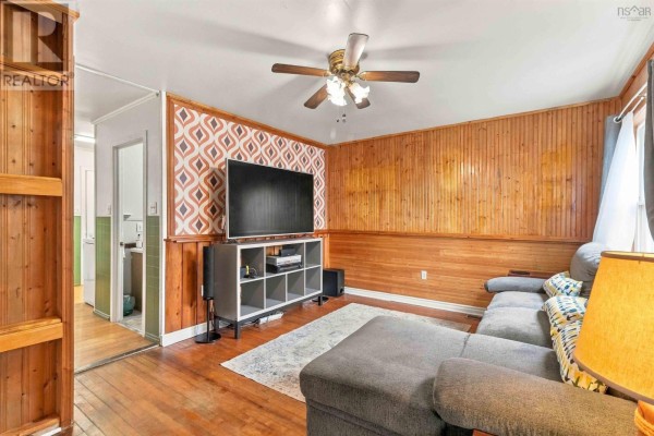 Living room with wood paneled walls and a view into the kitchen area. - 19 Central Boulevard, Liverpool